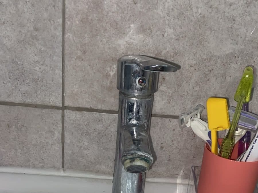 Llave monomando gastada sobre un lavamanos, antes del recambio