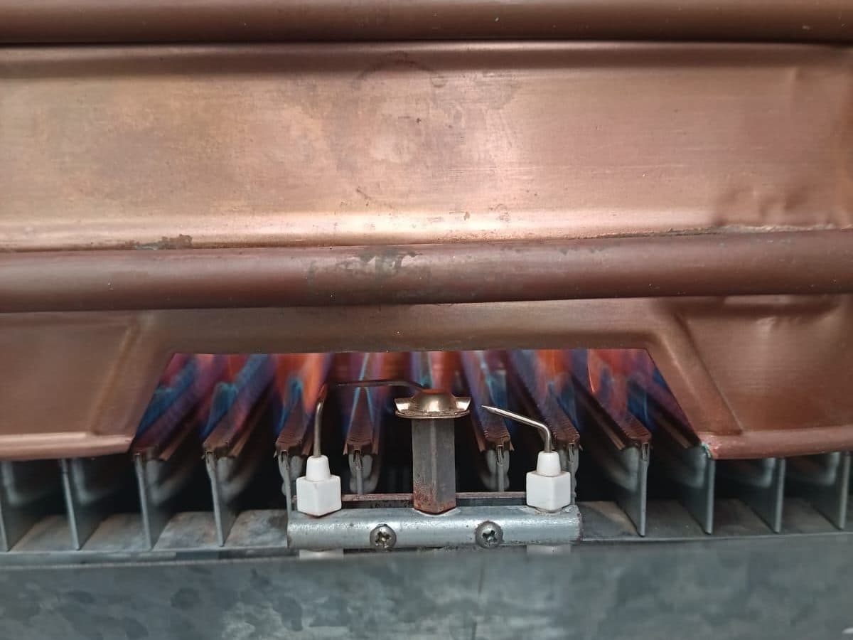 Quemador y serpentín de cobre de un calefont Rheem, abiertos para revisarlos y limpiarlos