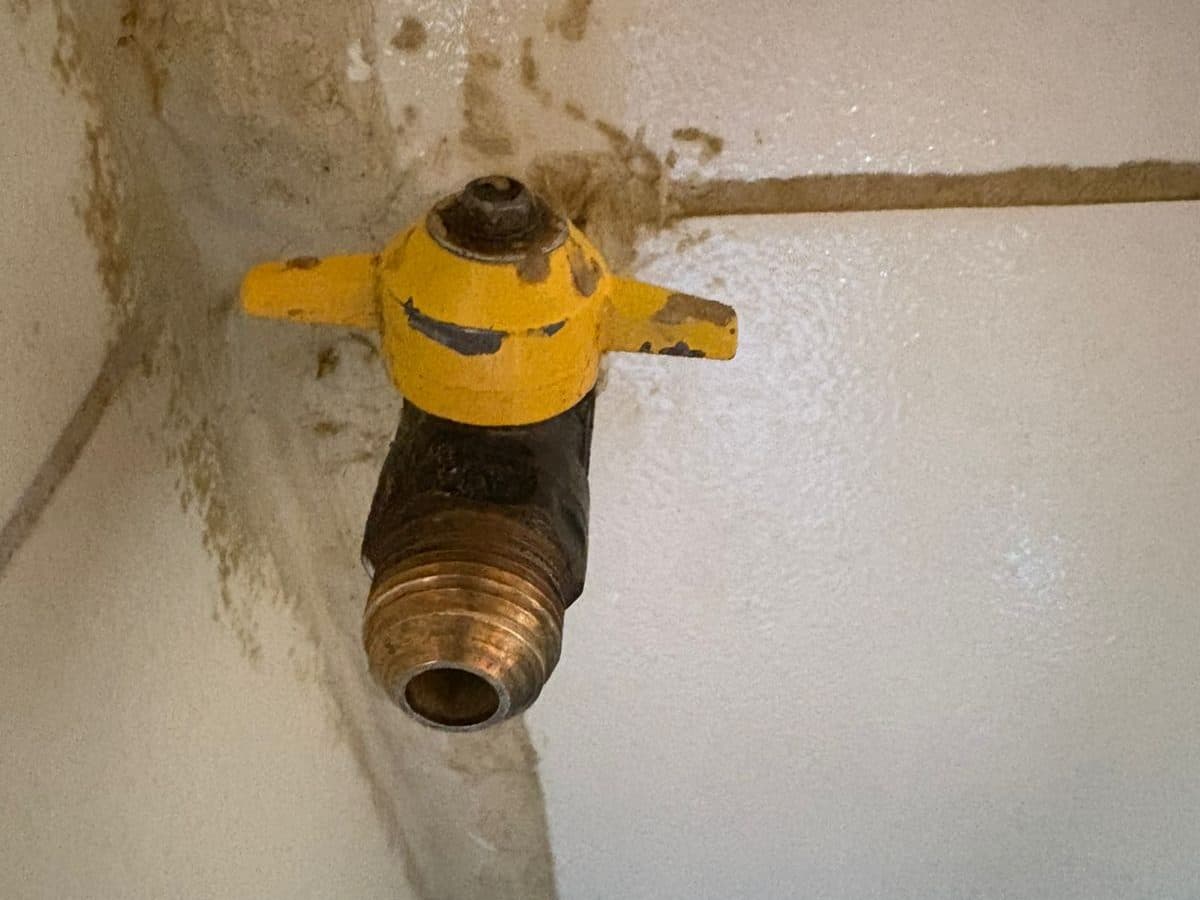Llave de paso de gas amarilla instalada en el muro, con su terminal de bronce para conectar el artefacto