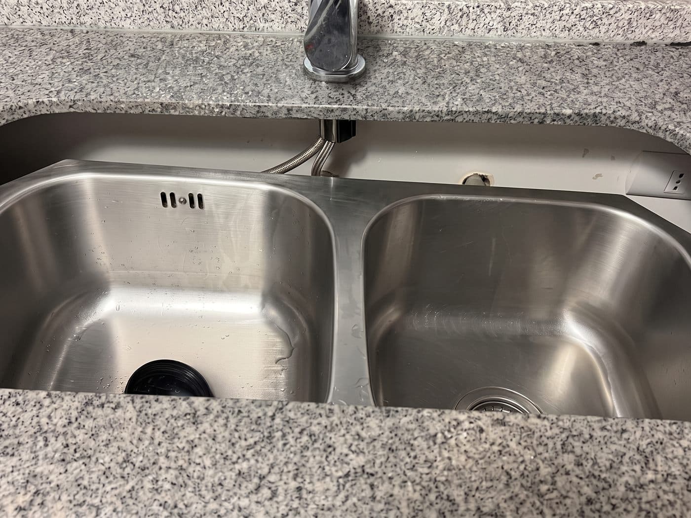 Lavaplatos de acero inoxidable de dos cubetas instalado bajo una cubierta de granito