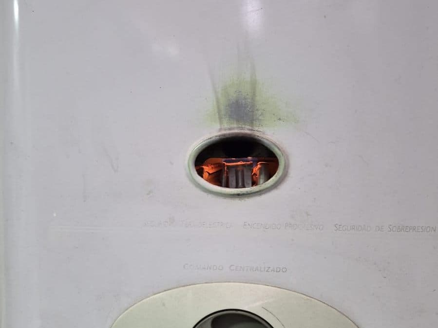 Calefont encendido con la llama visible en la mirilla después de la reparación