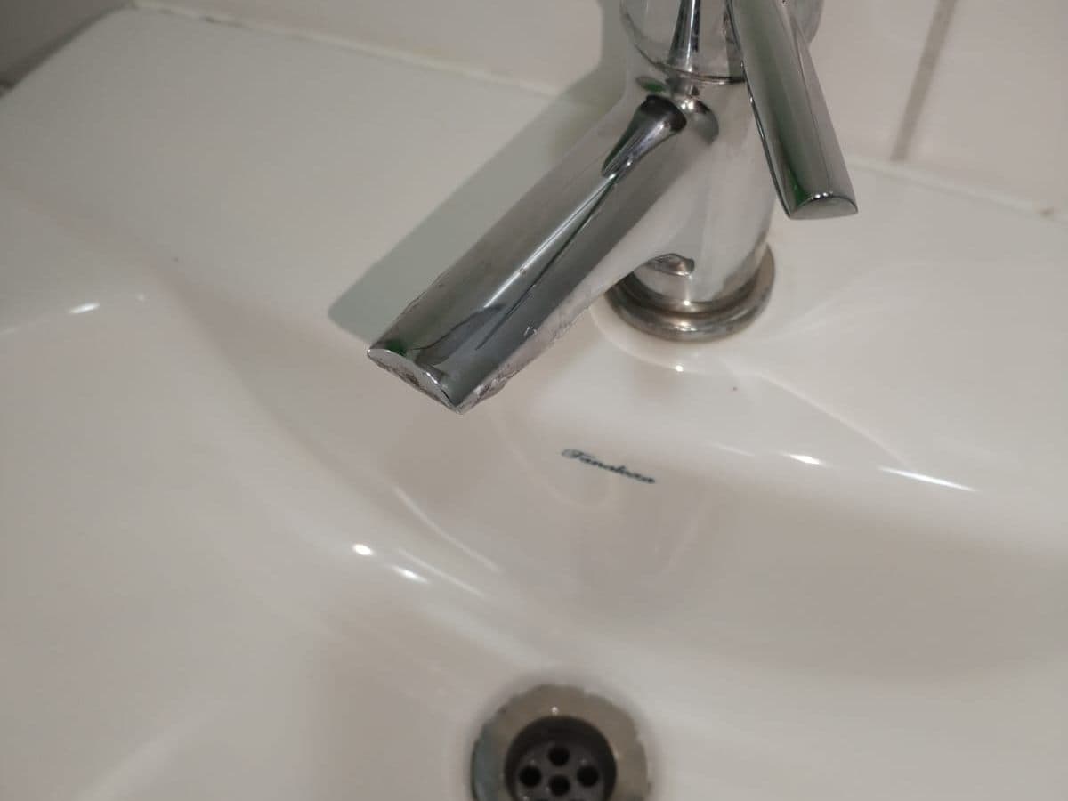 Llave monomando cromada nueva instalada en un lavamanos de loza