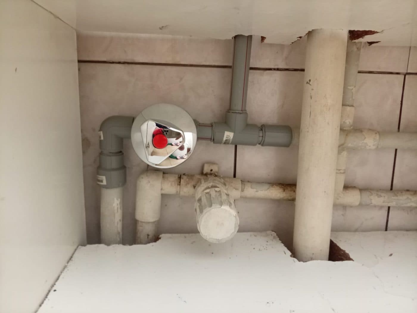 Llave de paso y cañerías a la vista bajo un mueble, con el fondo abierto para llegar a las uniones